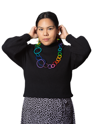 A young woman in a black top wearing a multicolored plastic chain necklace.