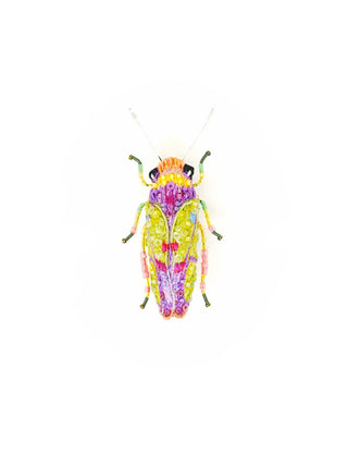 An embroidered brooch in the form of a yellow and purple sharpshooter beetle.