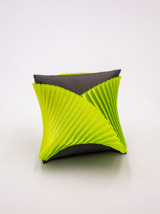 A green pleated silk cuff bracelet on a gray pillow.