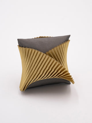 An olive pleated silk cuff bracelet on a gray pillow.