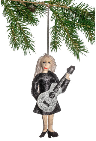 A felt ornament of Taylor Swift in a glittery dres, holding a guitar, hanging from a holiday tree.
