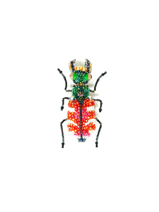 An embroidered brooch in the form of a red and green tiger beetle.