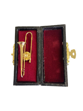 A lapel pin that looks like a gold trombone in a red, velvet-lined case.