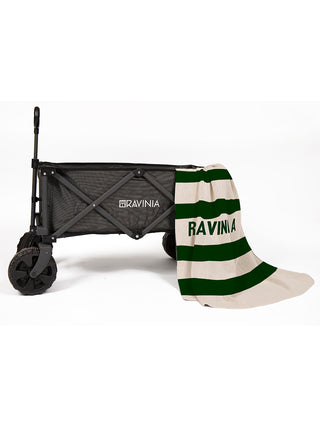 A black Ravinia wagon with a cream-colored and green striped blanket with the word Ravinia on it, hanging from the wagon.