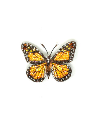A hand-embroidered brooch in the shape of an orange wanderer monarch butterfly.
