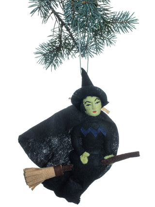 A felt ornament on a tree branch depicting the Wicked Witch of the West on a broom.