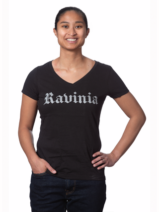 A smiling woman in a black v-neck tee with the word Ravinia in silver gothic letters.