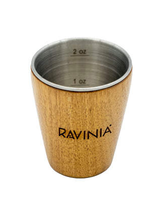 Acacia wood shot glass with Ravinia etched and a stainless steel interior, showing the 1 oz and 2 oz markings inside.
