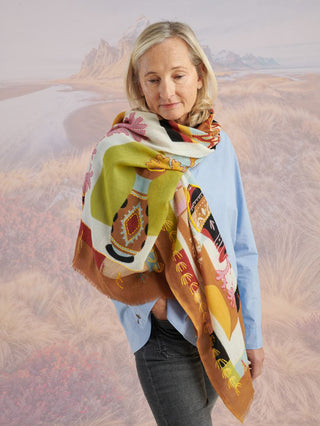 A woman wearing a colorful scarf around her neck and draped over one shoulder to show an embroidered vase.