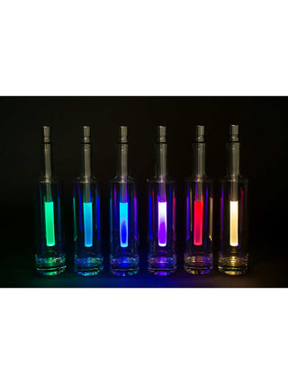 Six bottlelights sitting in clear bottles and displaying various colors, in the dark.