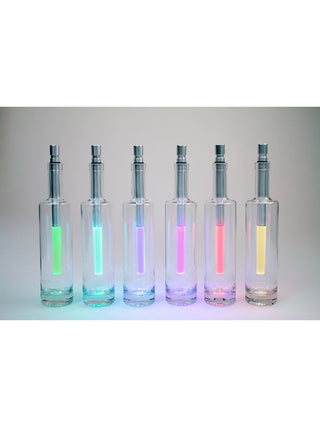 Six bottlelights sitting in clear bottles and displaying various colors, on a light background.