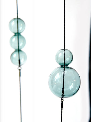 Aqua colored glass beads hung on black wire.