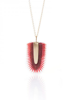 A brass chain necklace with a red pendant made of drum leather.