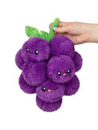 A hand holding a plush stuffie of purple grapes with a green stem. Some of the grapes have smiling faces.