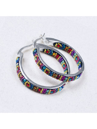 A pair of silver round hoop earrings with  crystals on the inside and outside.