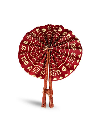 A hand fan made with red patterned fabric and leather handles.