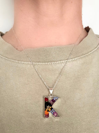 A model wearing the K initial pendant with a silver chain around their neck.