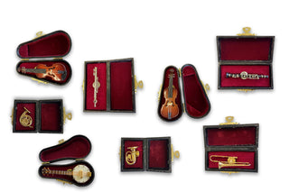 Pins in the shape of a violin, french horn, banjo, flute, tuba, cello, clarinet, and trombone, all in black and red cases.