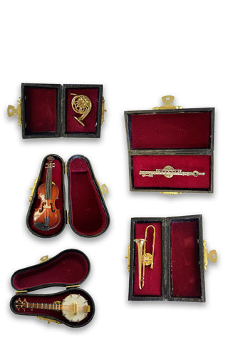 Pins in the shape of a french horn, violin, banjo, flute, and trombone, all in black and red cases.