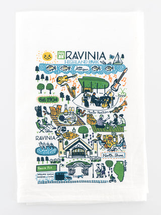 A white kitchen towel, folded, with an illustrated pattern of various places and scenes from Ravinia Festival.