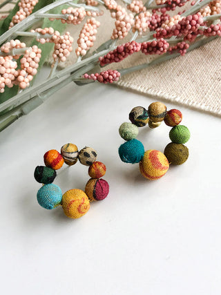 A pair of post earrings made up of 8 wooden beads wrapped in colorful Kantha fabrics.