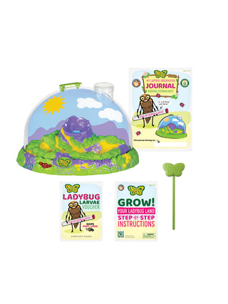 A domed ladybug habitat next to a journal, growing and care instructions, a prepaid ladybug voucher, and a water dropper.