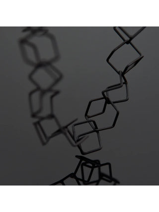 A close-up of a matte black bracelet made of linked cube-like pieces.