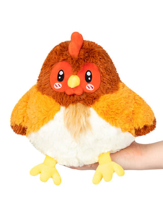 A plush hen stuffed animal sitting on a hand.