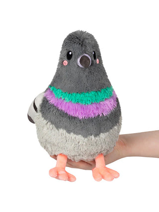 A stuffed animal gray pigeon sitting on a hand.