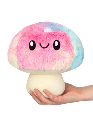 A plush tie dyed mushroom with a smiling face sitting atop a hand.