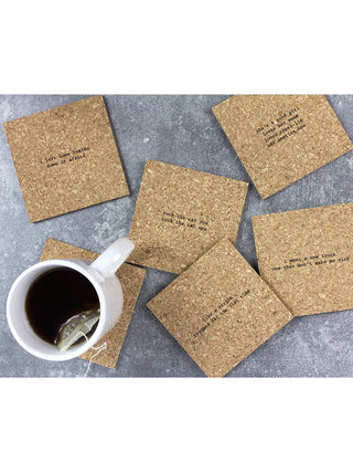6 cork coasters with mistaken lyrics from 80s songs spread out on a table with a cup of tea.