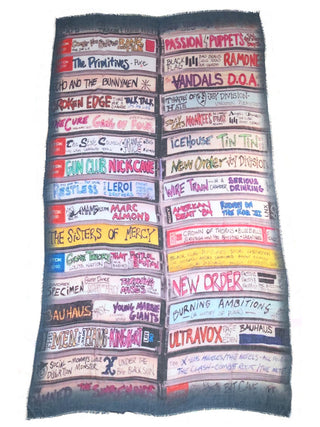 A rectangular scarf that looks like two rows of cassette mix tapes, with handwritten names of various bands from the eighties.