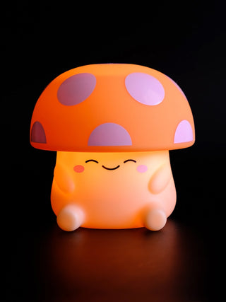 A squishy silicone mushroom night light with a orange and white spotted cap.