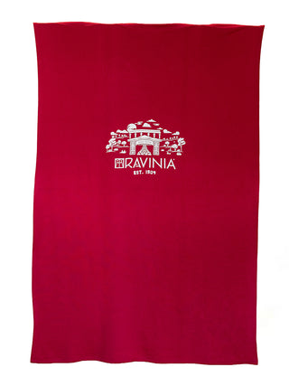 A red sweatshirt blanket with a white Ravinia branded design, laid flat.