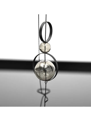 A close-up view of two black metal rings and two glass beads stacked on a black wire.