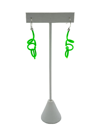 Green twisty earrings hanging on a white earring holder.