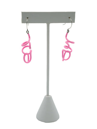 Pink twisty earrings hanging on a white earring holder.