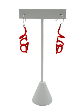 Red twisty earrings hanging on a white earring holder.