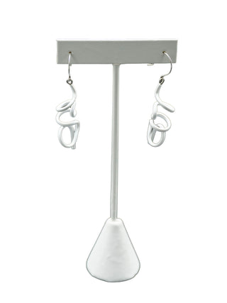 White twisty earrings hanging on a white earring holder.