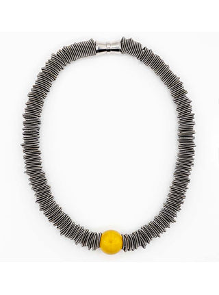 An oval necklace made of slate-colored spring rings, with one large yellow porcelain bead at the bottom.