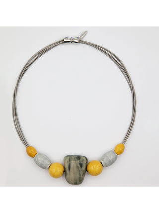 A necklace flat with a magnetic clasp at the top, and seven large beads at the bottom.