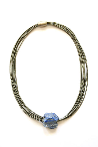 A necklace with slate-colored strands with a blu-tinged chunk of stone at the bottom.