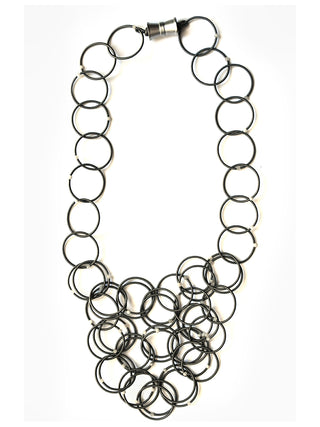Slate-colored loops of piano wire adorned with moonstone form a necklace, with a magnetic clasp.