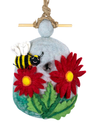 A hanging felt birdhouse with two red flowers, a leaf underneath and a happy bumblebee.