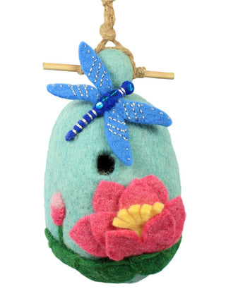 A blue felt birdhouse hanging from a cord with a large, bright blue dragonfly above the opening and a large pink flower below.