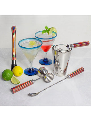 A four piece barware set, each piece with a vibrantly colored handle, shown with mixed drinks and a lemon and lime.