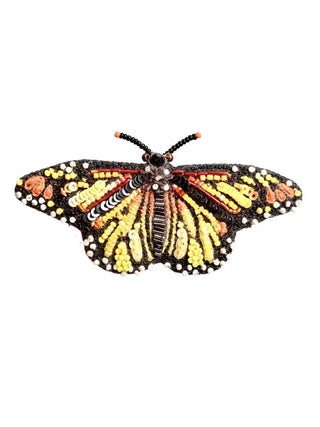 An embroidered brooch in the form of a monarch butterfly, orange, yellow and red.
