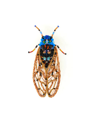 An embroidered pin in the form of a cicada, with gold wings, a black and red back, and bright blue head.