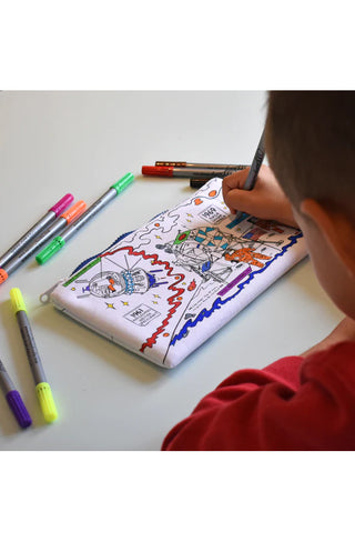 An overhead view of a young boy coloring in the astronauts side of a space-themed pencil case.