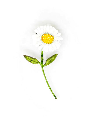 An embroidered brooch in the form of a white daisy, with a bright yellow center and green stem and leaves.
